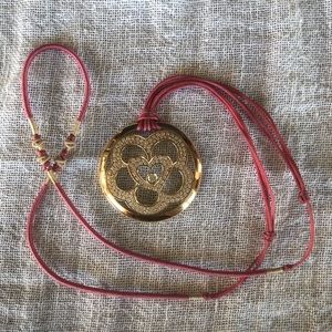 Escada 18 karat yellow gold diamond pendant on silk cord.